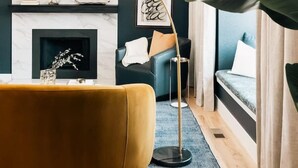 A modern living room with a sofa, floor lamp, fireplace, and large windows. - House of Noir Elan Stunning 6BR Designer Retreat (Arvada)