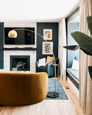 A modern living room with a sofa, floor lamp, fireplace, and large windows. - House of Noir Elan Stunning 6BR Designer Retreat (Arvada)