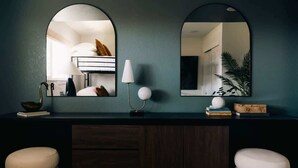 A room with a dark wooden desk, two white stools, a lamp, a mirror, and a plant. - House of Noir Elan Stunning 6BR Designer Retreat (Arvada)