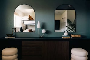 A room with a dark wooden desk, two white stools, a lamp, a mirror, and a plant. - House of Noir Elan Stunning 6BR Designer Retreat (Arvada)