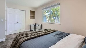 A bedroom with a bed, a window, a door, and a small shelf. - Charming I Family Friendly I 4bd 2ba Arvada Home (Arvada)