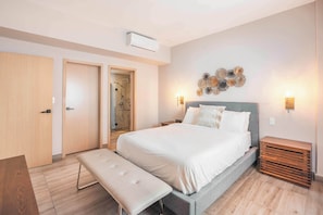 Ein Schlafzimmer mit Bett, Bank, Nachttischen und einer Duschkabine.
