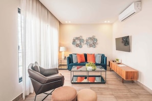 A modern living room with a sofa, coffee table, and ottomans. - Piantini Gem Modern Apartment with Amenities (Santo Domingo)