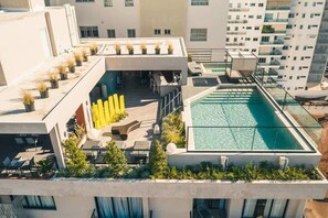 A rooftop pool area with a glass enclosure, outdoor seating, and potted plants. - Piantini Gem Modern Apartment with Amenities (Santo Domingo)