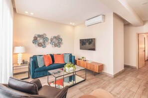 A modern living room with a sofa, coffee table, and a flat-screen TV. - Piantini Gem Modern Apartment with Amenities (Santo Domingo)