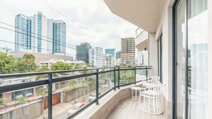 A balcony with a city view, a table with chairs, and a glass railing. - Stylish Apartment in Piantini Pool & Gym u302 (Santo Domingo)