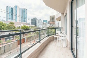 Ein Balkon mit Blick auf die Stadt, inklusive Tisch, Stühlen und einer Glasumlaufung.