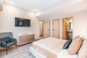 Ein modernes Schlafzimmer mit Bett, Sofa, Fernseher und Kleiderschrank.