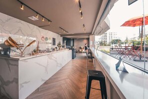 Eine moderne Bar mit Marmorplatte, Barhocker und Blick auf die Stadt durch große Fenster.