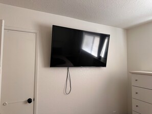 A flat-screen TV mounted on a wall with a cable hanging below it. - 3-bedroom house-Sloan park -with cool AC -ping pong table (Mesa)