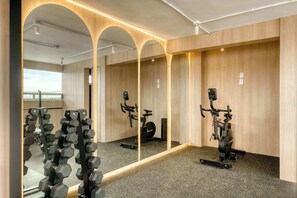 Ein Fitnessstudio mit Trainingsgeräten, Spiegeln und Blick nach draußen.