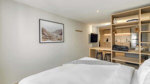 A modern hotel room with a bed, a desk, a TV, and a built-in kitchen area. - Modern King Studio in Central Roma Norte (Ciudad de México)