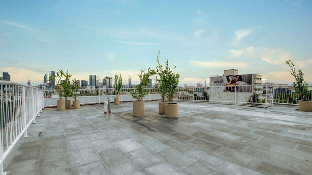 A rooftop terrace with potted plants, a white railing, and a city skyline in the background. - Modern King Studio in Central Roma Norte (Ciudad de México)