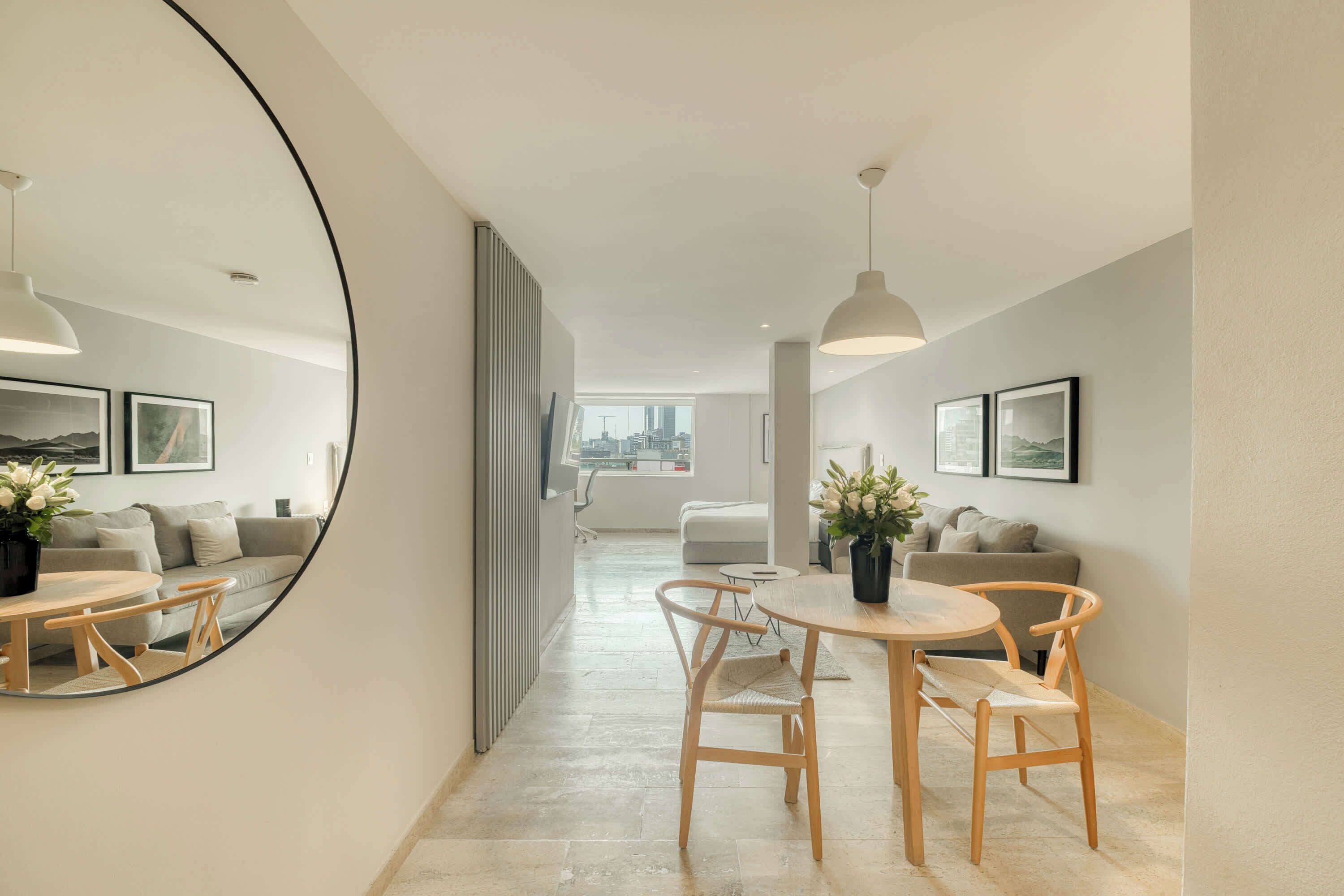 Een modern interieur met een eethoek, een grote spiegel en uitzicht op de stad.