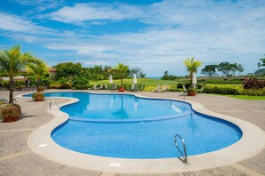 A swimming pool with a curved design, surrounded by lounge chairs and potted plants. - Del Mar 4N - 3 bdr 2 bath Family (Playa Herradura)