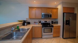 A modern kitchen with wooden cabinets, stainless steel appliances, a double sink, and a tiled backsplash. - Del Mar 4N - 3 bdr 2 bath Family (Playa Herradura)