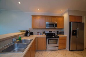 A modern kitchen with wooden cabinets, stainless steel appliances, a double sink, and a tiled backsplash. - Del Mar 4N - 3 bdr 2 bath Family (Playa Herradura)