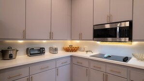 Eine moderne Küche mit grauen Schränken, einer Edelstahl-Mikrowelle, einem Toaster und einem Topf auf der Arbeitsfläche.