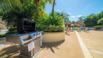 Un espace barbecue extérieur avec un coin salon aménagé au bord de la piscine.