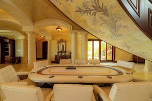 A luxurious room with a central round table, seating, and a decorative ceiling. - Casa Garmus - 10 bdr Ocean View (Playa Herradura)