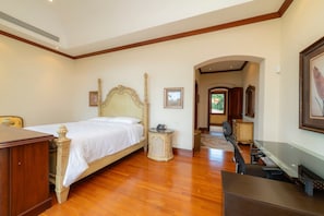 A bedroom with a wooden bed, a desk, a chair, and a small table with a telephone. - Casa Garmus - 10 bdr Ocean View (Playa Herradura)