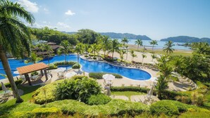 A resort with a large, winding pool surrounded by palm trees and a beach. - Casa Garmus - 10 bdr Ocean View (Playa Herradura)
