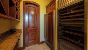 A kitchen with wooden cabinetry, a built-in oven, and a wine rack. - Casa Garmus - 10 bdr Ocean View (Playa Herradura)
