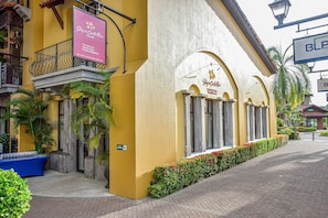 A hotel with a yellow facade, a balcony with a wrought iron railing, and a signboard advertising services like tour desk and vacation rentals.