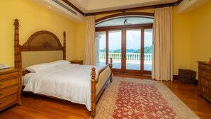 A bedroom with a large bed, wooden headboard, a view of a balcony, and a patterned rug. - Casa Garmus - 10 bdr Ocean View (Playa Herradura)