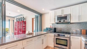 A modern kitchen with white cabinets, stainless steel appliances, and a granite countertop. - Apt with 2br-beachfront private pool in Sotogrande (Punta Cana)