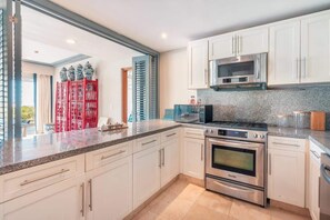 A modern kitchen with white cabinets, stainless steel appliances, and a granite countertop. - Apt with 2br-beachfront private pool in Sotogrande (Punta Cana)