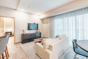 A modern living room with a sofa, coffee table, and TV on a black cabinet. There is a dining area with chairs and a table. - Santo Domingo Oasis Modern Apartment with Gym u203 (Santo Domingo)