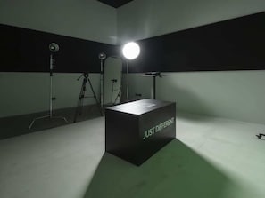 Valokuvausstudio, jossa on musta tausta, jossa lukee teksti ”JUST DIFFERENT”, sekä valaistuslaitteita.