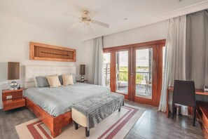 Ein Schlafzimmer mit einem großen Bett, einem Schreibtisch, einem Stuhl und einem Balkon mit Blick.