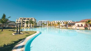 A resort with a large swimming pool, palm trees, and multi-story buildings with balconies. - Studio 3 guests Balcony with views Fishing lodge 1090 (Punta Cana)