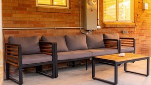 Eine Ziegelwand, ein graues Sofa mit Holzlatten und ein Holztisch.