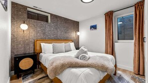Ein Schlafzimmer mit einem Bett, einem runden Lautsprecher, einer Wand-Klimaanlage und einem Fenster mit Vorhängen.