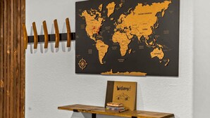 Eine Weltkarte an der Wand, ein hölzerner Kleiderständer und ein Willkommensschild auf einem Tisch.