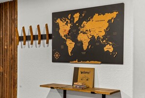 A world map on a wall, a wooden coat rack, and a welcome sign on a table. - Modern Arvada Hotspot Sauna & Games (Arvada)