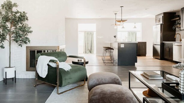 Ein modernes Wohnzimmer mit einem grünen Sofa, Poufs, einem Couchtisch und einem Kamin.