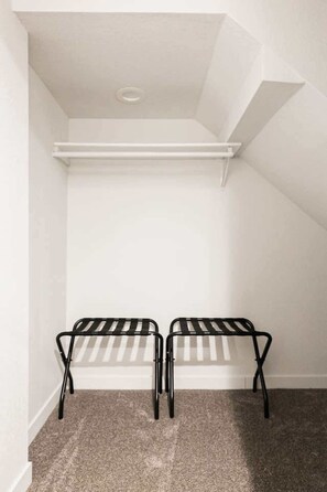 Ein kleiner, abgeschlossener Raum mit schrägverdeckter Decke, einer weißen Wand und einem Teppichboden.
