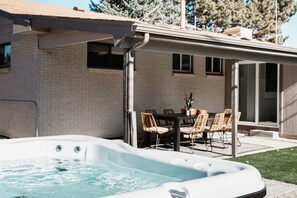 Ein Whirlpool neben einem Backsteinhaus mit überdachter Terrasse.