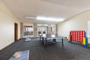 A room with a ping pong table, a red and yellow obstacle course, and a stone wall. - The Canopy at Table Rock Lake (Kimberling City)