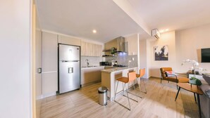 A modern kitchen with a stainless steel refrigerator, granite countertops, and a small dining area with bar stools. - Breakfast Included at Regatta Living 906 (Santo Domingo)