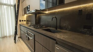 A modern kitchen with a stainless steel sink, a gas stove, and a black faucet. - Cozy Urban Loft 1br near Coast (Panamá)