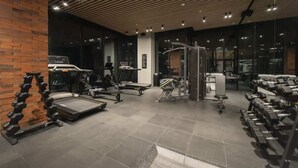 Un gimnasio con diverso equipo de ejercicio, una pared de ladrillo y un techo de listones de madera.