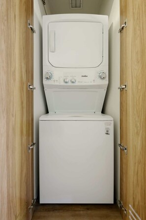 A compact, white washing machine and dryer unit installed in a wooden cabinet with metal hinges. - Cozy Furnished Studio in Mexico City U203 (Ciudad de México)