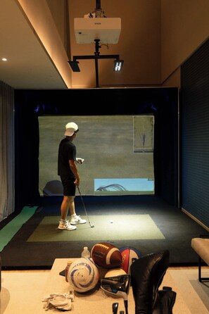 A room with a projection screen, a golf cart, and sports equipment. - Cozy Furnished Studio in Mexico City U203 (Ciudad de México)