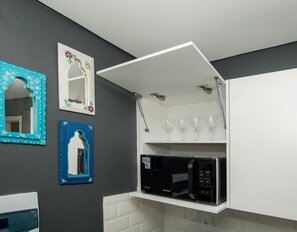 A kitchen with a microwave, wine glasses, and decorative mirrors. - First Living 206  Natalia Sosa Ibarra New 1BR with Desk & Premium King-Size Bed (Asunción)