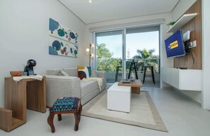 Ein modernes Wohnzimmer mit einer Couch, einem Couchtisch und einem an der Wand befestigten Fernseher.